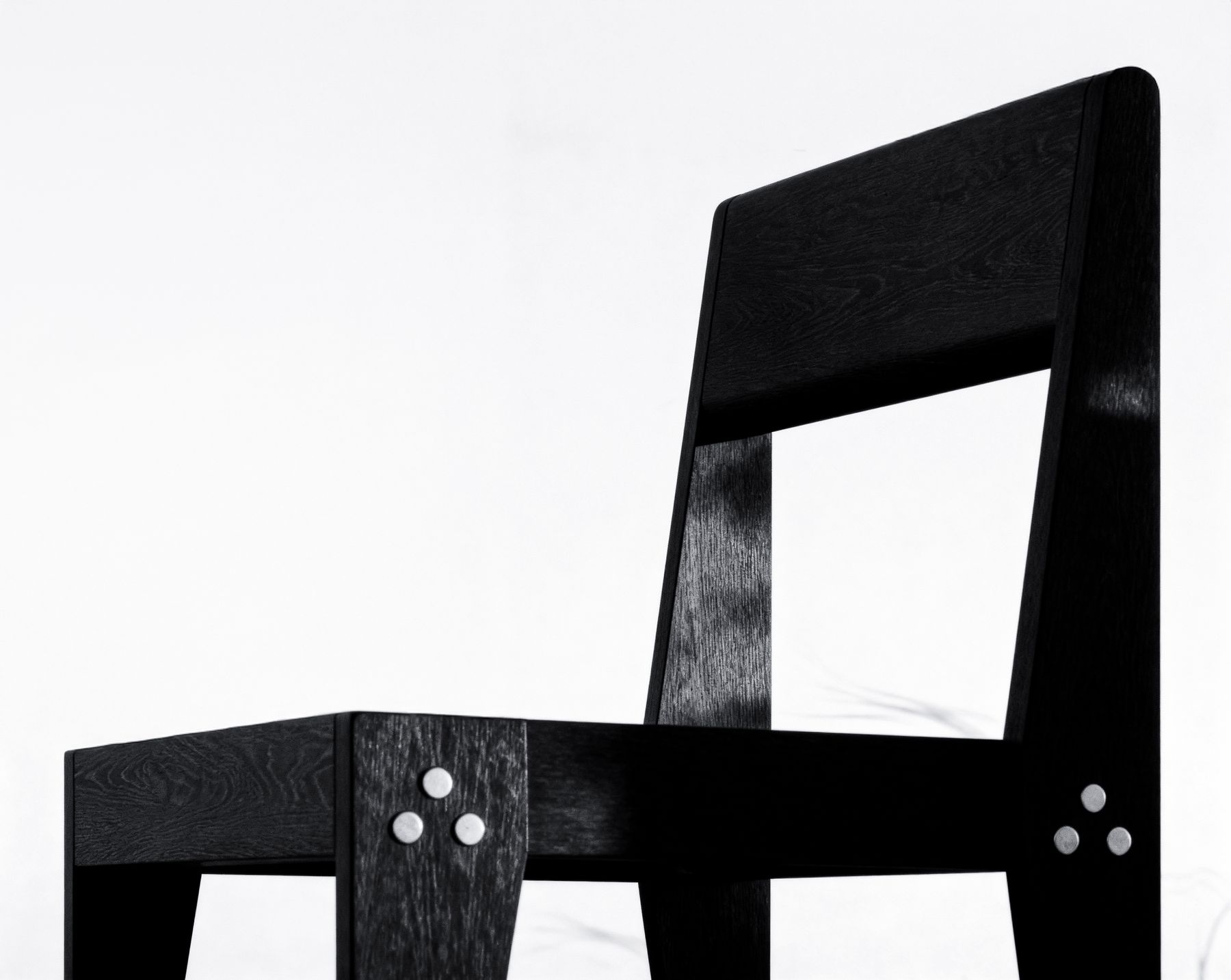 Close-up of The Chair's backrest and seat frame, with the burned grain and the bolt cluster visible