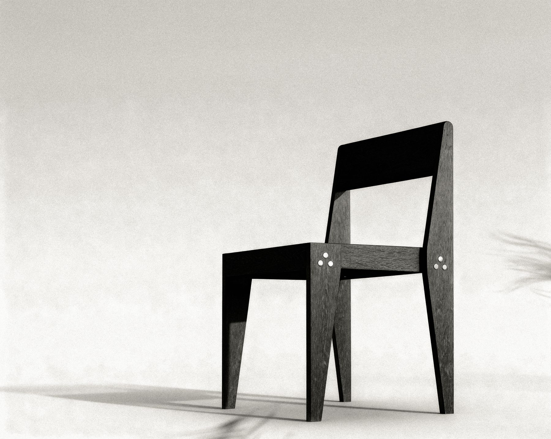 Black-and-white studio photograph of an earlier version of The Chair, showing the tapered legs and the three-bolt clusters at the seat joints